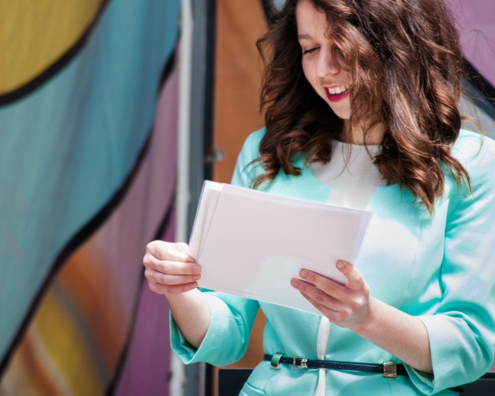 Beautiful young business girl in a blue jacket holds white sheets in hands